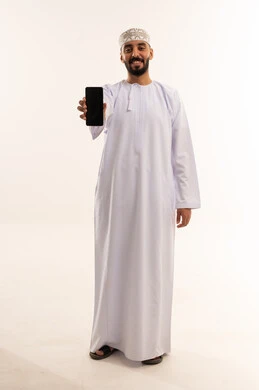 رجل عماني بالزي التقليدي يمسك هاتف ذكي