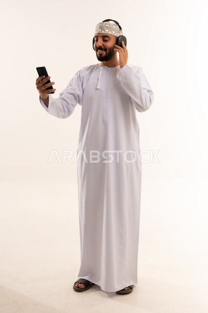 رجل عماني يستخدم الهاتف الذكي وسماعات الرأس في استوديو