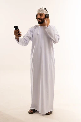 Omani Man Using Smartphone and Headphones on White Background