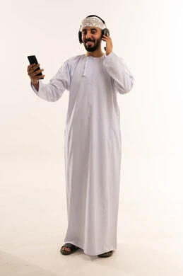 رجل عماني يرتدي سماعات ويمسك هاتفه في الاستوديو