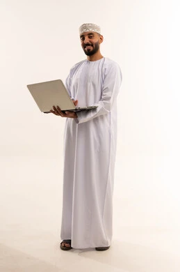 رجل عماني بالزي التقليدي يحمل جهاز حاسوب محمول
