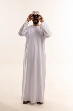 رجل عماني باللباس التقليدي يستخدم المنظار