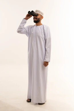 رجل عماني بالزي التقليدي ينظر من خلال المنظار