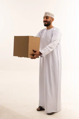 رجل عماني بالزي التقليدي يحمل صندوق كرتوني