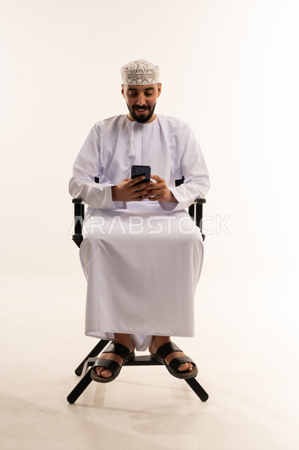 رجل عماني بالزي التقليدي يستخدم الهاتف الذكي