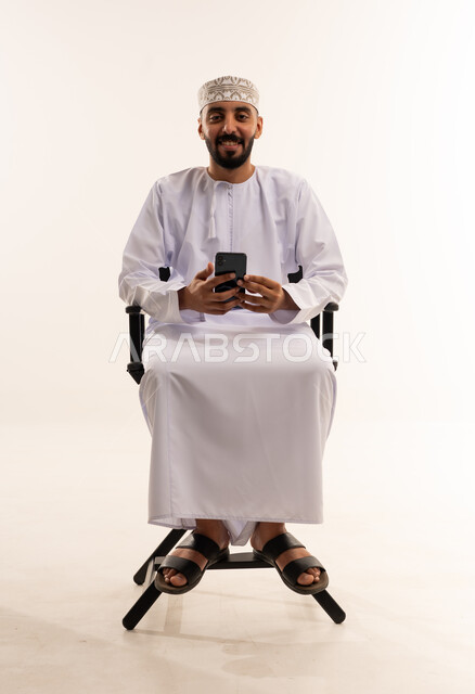 Omani Man in Traditional Dress Using Smartphone Studio