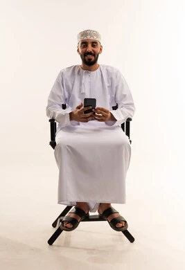 رجل عماني بالزي التقليدي يستخدم هاتف ذكي في استوديو
