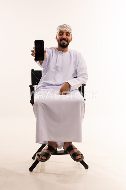 رجل عماني بالزي التقليدي يمسك هاتف ذكي