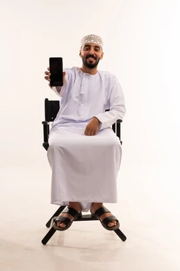 رجل عماني بالزي التقليدي يمسك هاتف ذكي