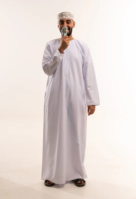 رجل عماني بالزي التقليدي يمسك أوراق نقدية