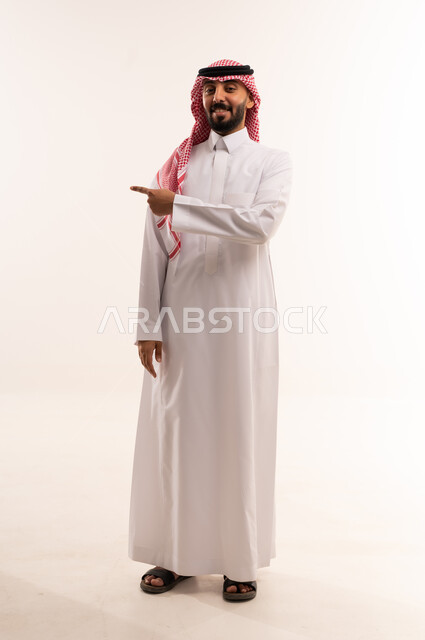 رجل سعودي بالثوب التقليدي يشير على خلفية بيضاء