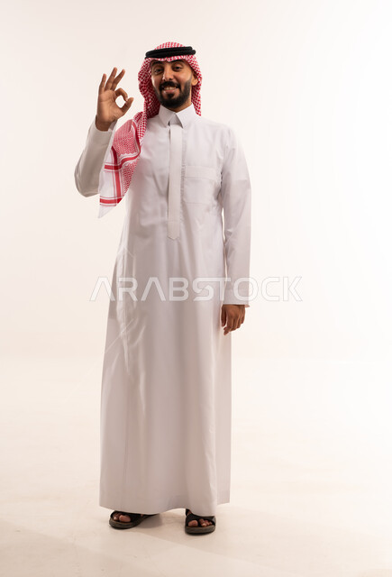 رجل سعودي بالزي التقليدي يرفع علامة الموافقة