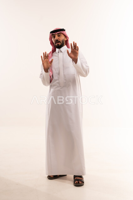 رجل سعودي بالزي التقليدي يرفع يديه بتعبير متفاجئ