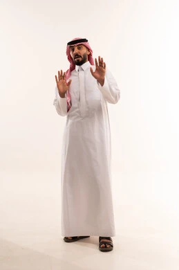 رجل سعودي بالزي التقليدي يرفع يديه بتعبير متفاجئ