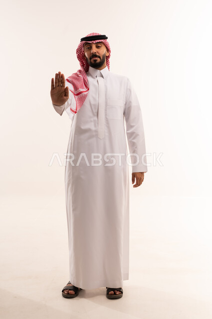 رجل سعودي بالزي التقليدي يشير بعلامة التوقف