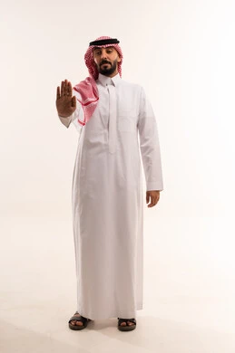 رجل سعودي بالزي التقليدي يشير بعلامة التوقف