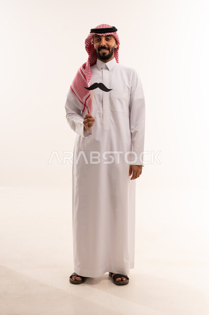 رجل سعودي بالثوب التقليدي يحمل شارباً ورقيًا