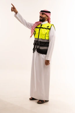 رجل سعودي بزي السلامة يشير للأعلى بخلفية بيضاء