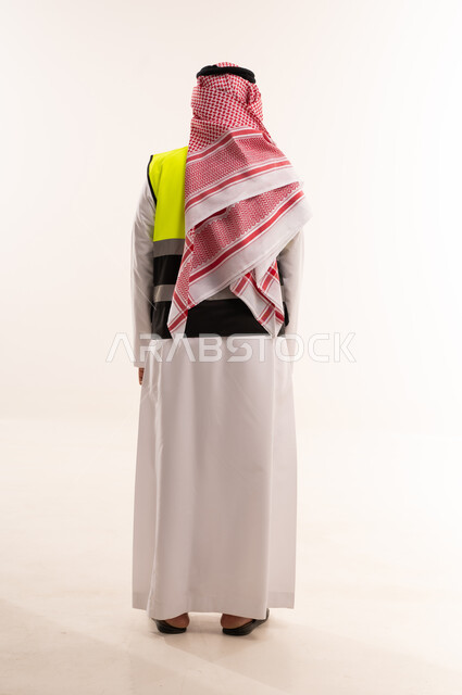 مهندس سعودي بالثوب التقليدي وسترة السلامة من الخلف