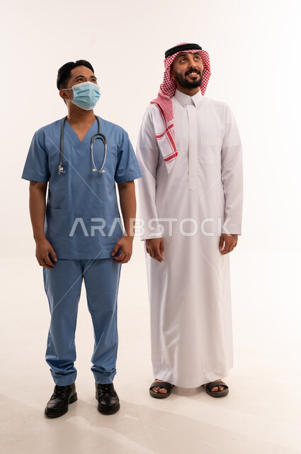رجل سعودي وممرض آسيوي بالزي الطبي الرسمي