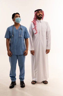 رجل سعودي وممرض آسيوي بالزي الطبي الرسمي