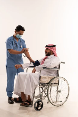 ممرض يقيس ضغط دم رجل سعودي على كرسي متحرك