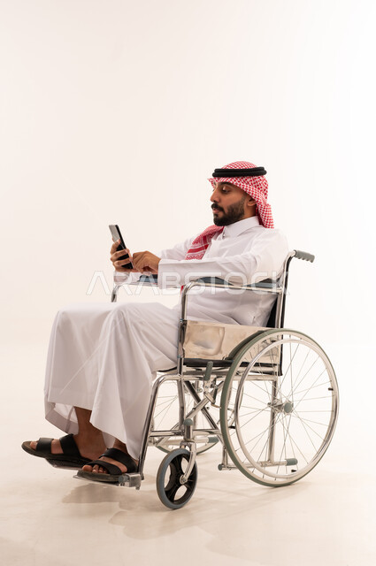 رجل سعودي على كرسي متحرك يستخدم الجوال