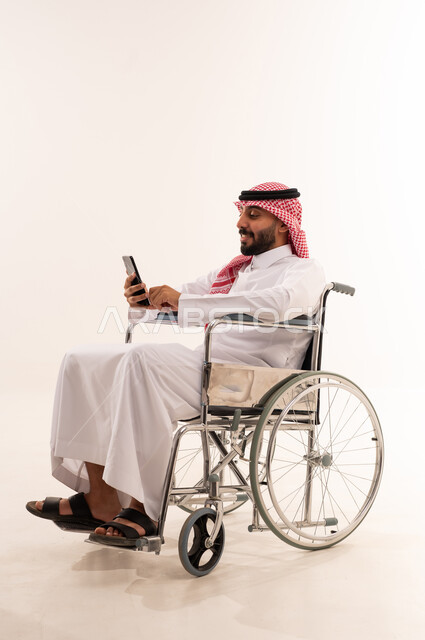 رجل سعودي على كرسي متحرك يستخدم الجوال