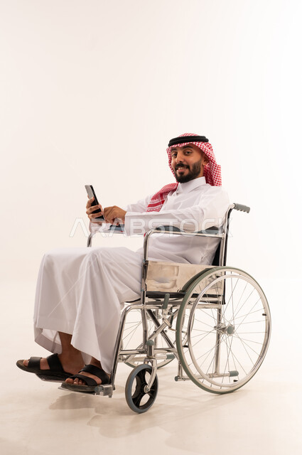 رجل سعودي على كرسي متحرك يستخدم الهاتف الذكي