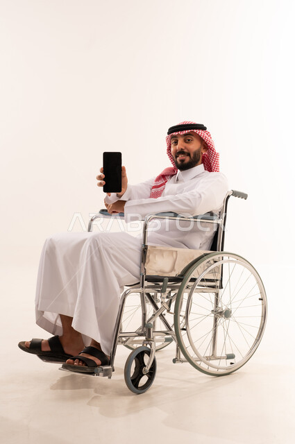 رجل سعودي على كرسي متحرك يحمل هاتف ذكي