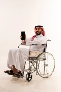 رجل سعودي على كرسي متحرك يحمل هاتف ذكي