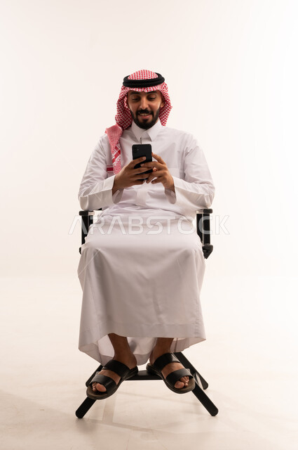رجل سعودي يستخدم الهاتف الذكي في استوديو أبيض
