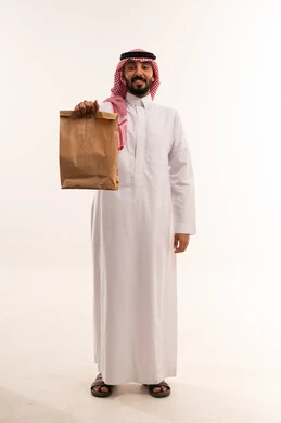 رجل سعودي بالزي التقليدي يحمل كيس توصيل