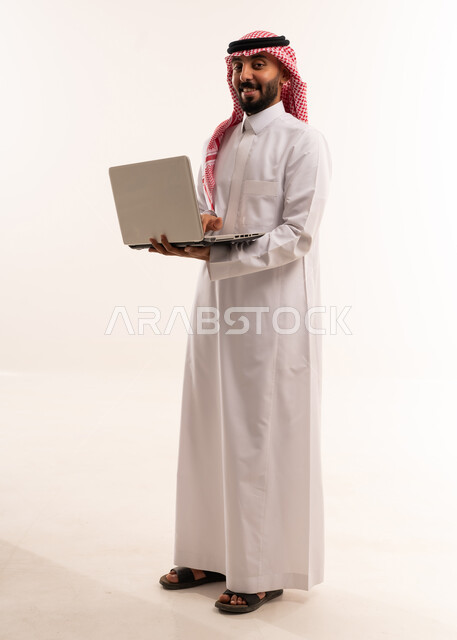 رجل سعودي بالثوب التقليدي يحمل جهاز محمول