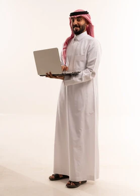 رجل سعودي بالثوب التقليدي يحمل جهاز محمول