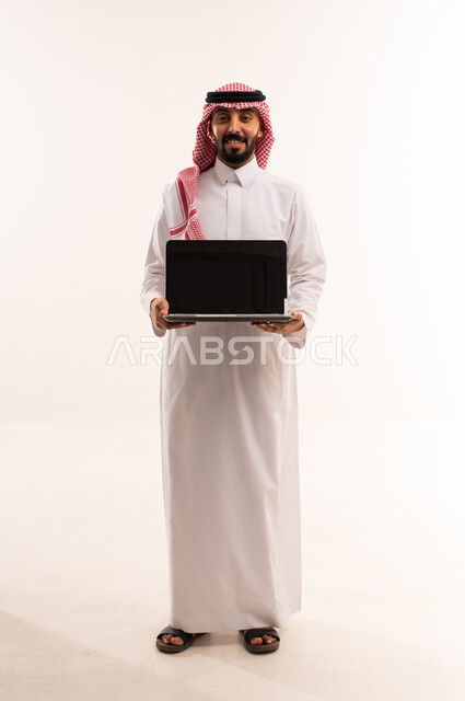رجل سعودي بالثوب يحمل جهاز حاسوب خلفية بيضاء