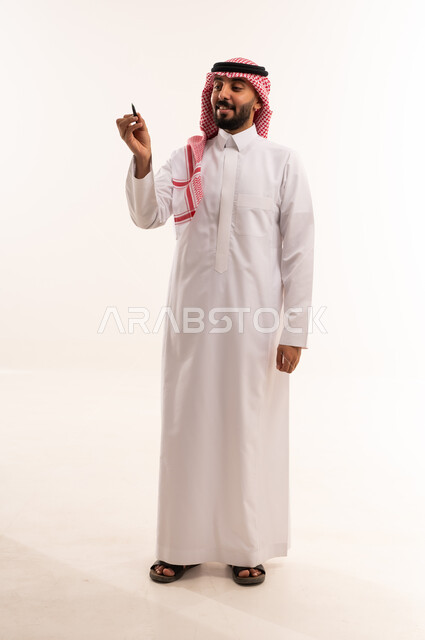 رجل سعودي بالثوب التقليدي يحمل قلماً