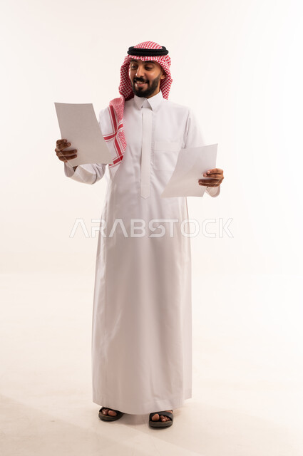 رجل سعودي بالثوب التقليدي يحمل أوراق عمل