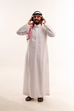 رجل سعودي بالثوب يرتدي سماعات رأس على خلفية بيضاء