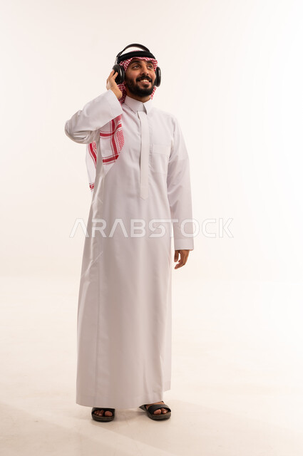 رجل سعودي يرتدي سماعات الرأس بالثوب التقليدي
