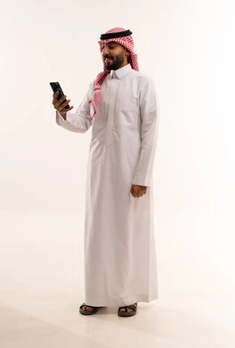 Saudi Man in Traditional Thobe Using Smartphone