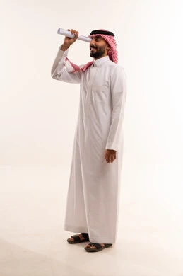 رجل سعودي بالثوب ينظر من خلال ورقة رؤية مستقبيلة