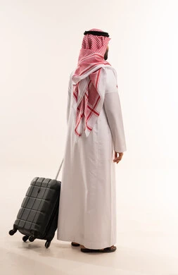 رجل سعودي مع حقيبة سفر يقف خلفية بيضاء