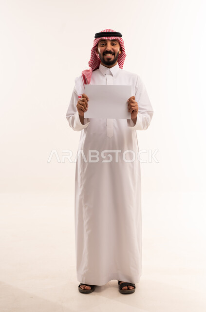 رجل سعودي بالزي التقليدي يحمل ورقة بيضاء فارغة