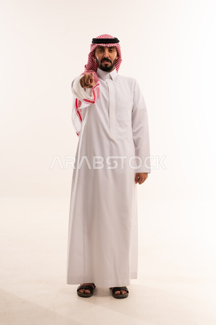 رجل سعودي بالزي التقليدي يشير بإصبعه للكاميرا