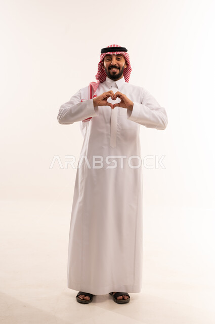 رجل سعودي بالزي التقليدي يشكل قلب بيديه