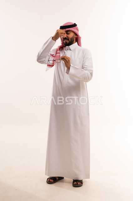 رجل سعودي بالثوب التقليدي يمسك نظارته الطبية