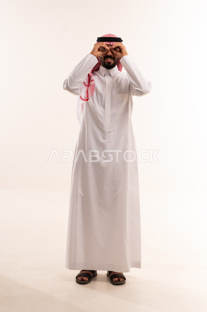 رجل سعودي بالزي التقليدي يضع يديه كمنظار