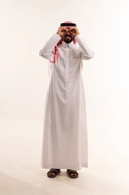 رجل سعودي بالزي التقليدي يضع يديه كمنظار