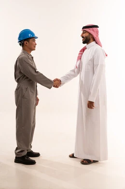 رجل أعمال سعودي يصافح عامل صناعي آسيوي